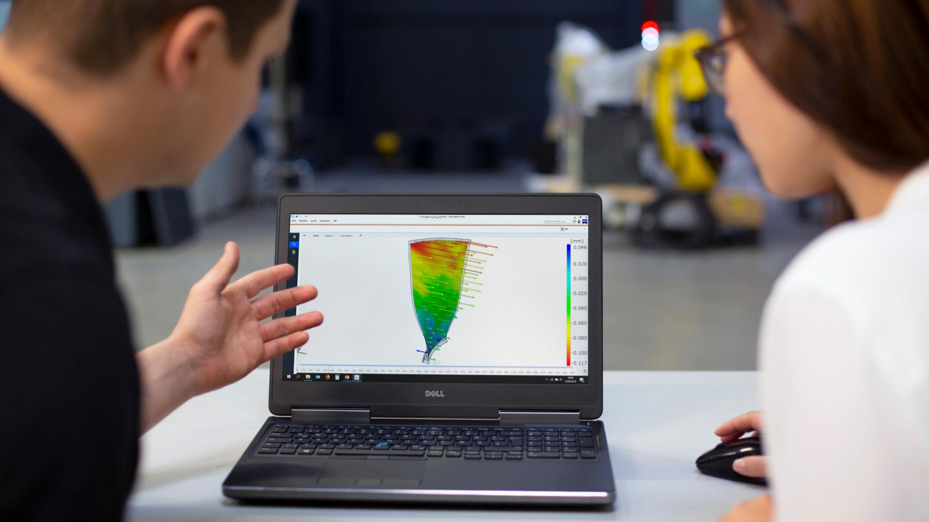 Zwei Analysten betrachten die Ergebnisse der Schwingungsanalyse auf einem Laptop