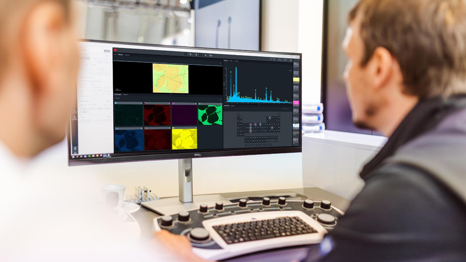 Zwei Menschen sitzen vor einem Monitor auf dem verschiedene Graphen und technische Darstellungen zu sehen sind
