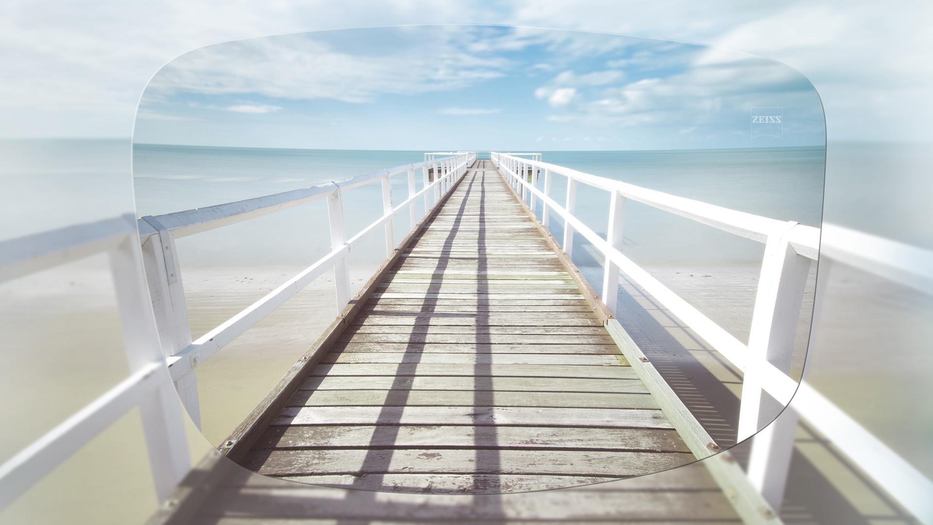 Blick durch ein ZEISS Einstärken-Lagerglas auf einen Pier an einem sonnigen Tag 