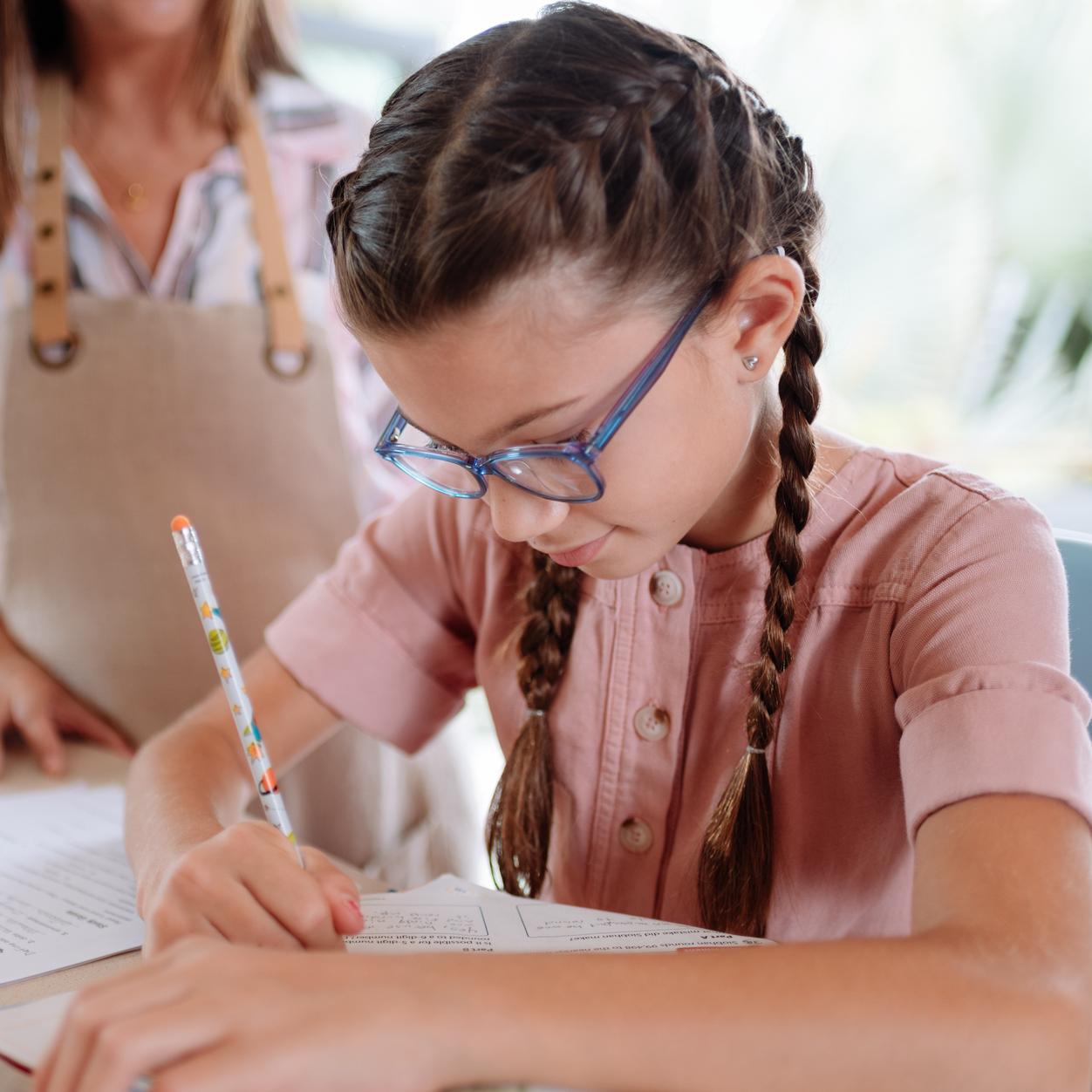 Mädchen mit Brille schreibt mit Stift