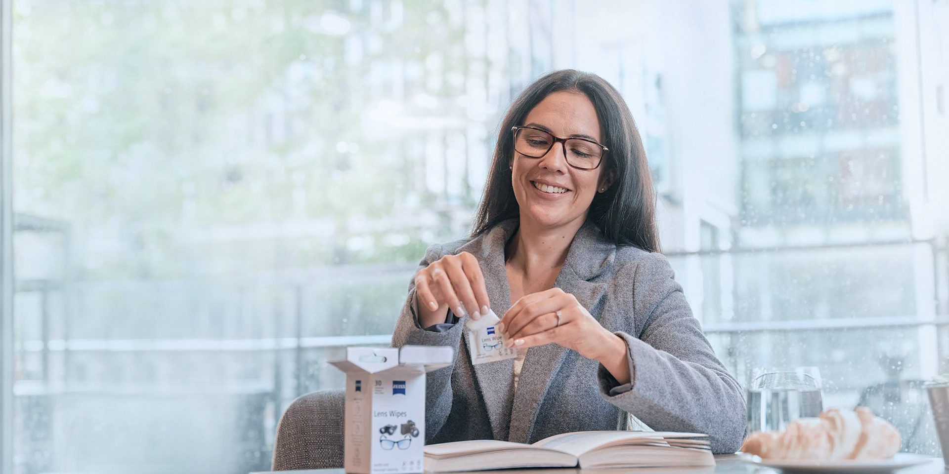 Eine Frau öffnet die Verpackung eines Brillenreinigungstuchs