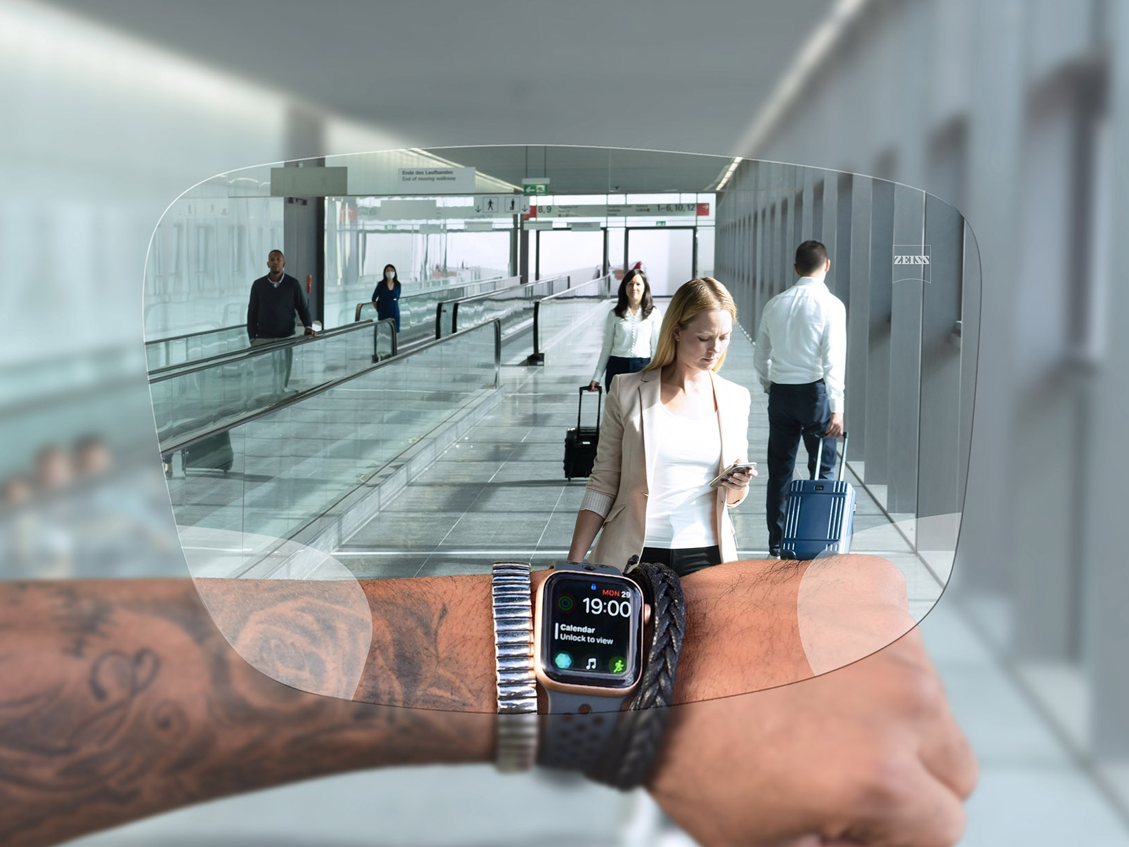 Jemand wirft durch ZEISS SmartLife Digital Brillengläser einen Blick auf die Uhr. Im Hintergrund sieht man eine typische Flughafensituation mit Menschen auf Rolltreppen oder beim Schieben ihrer Koffer. 